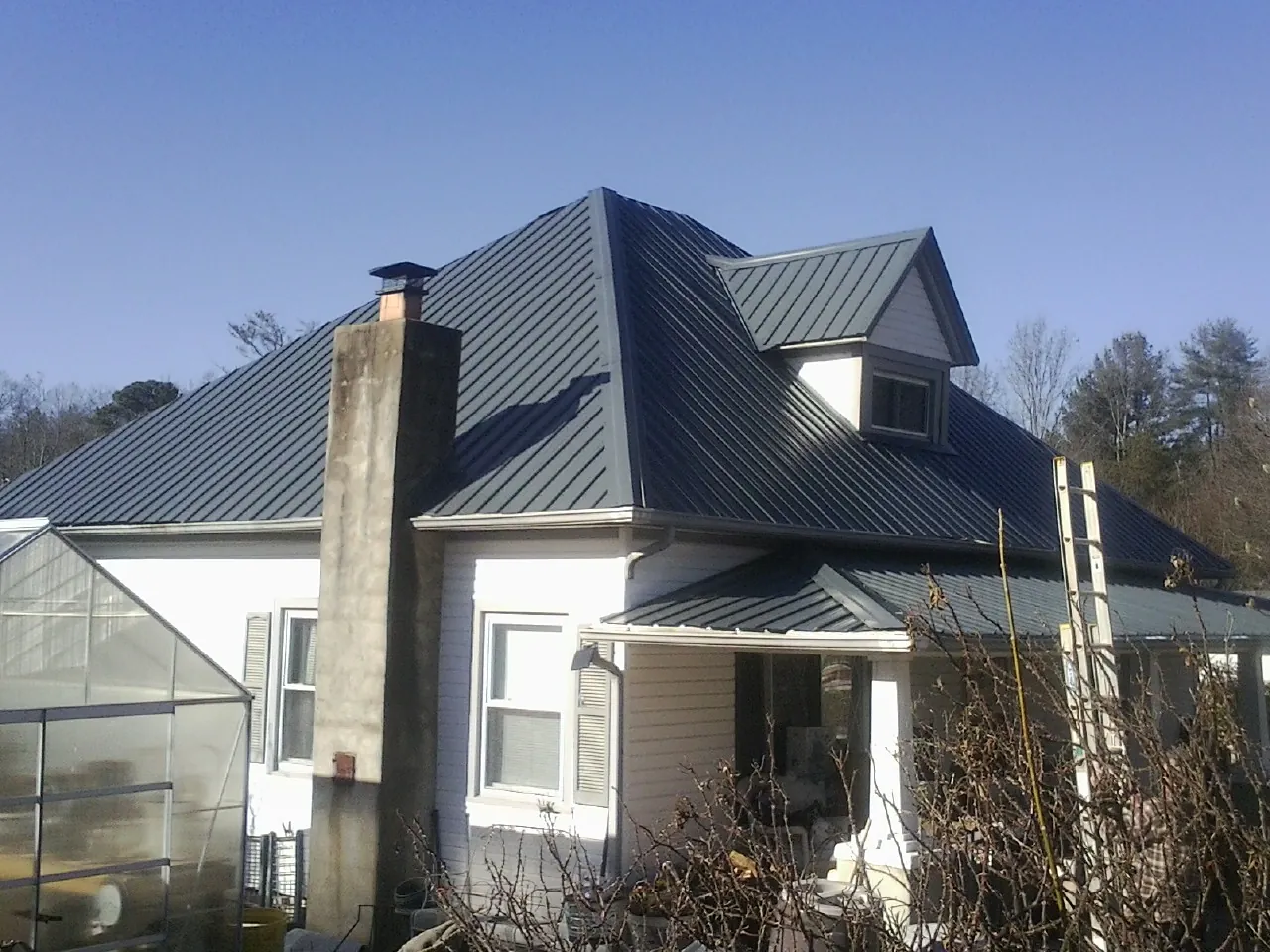 Dark blue standing seam metal roof on a white farmhouse with dormer — Slate & Tile Roof Repair by Roofing Brothers in Shamokin