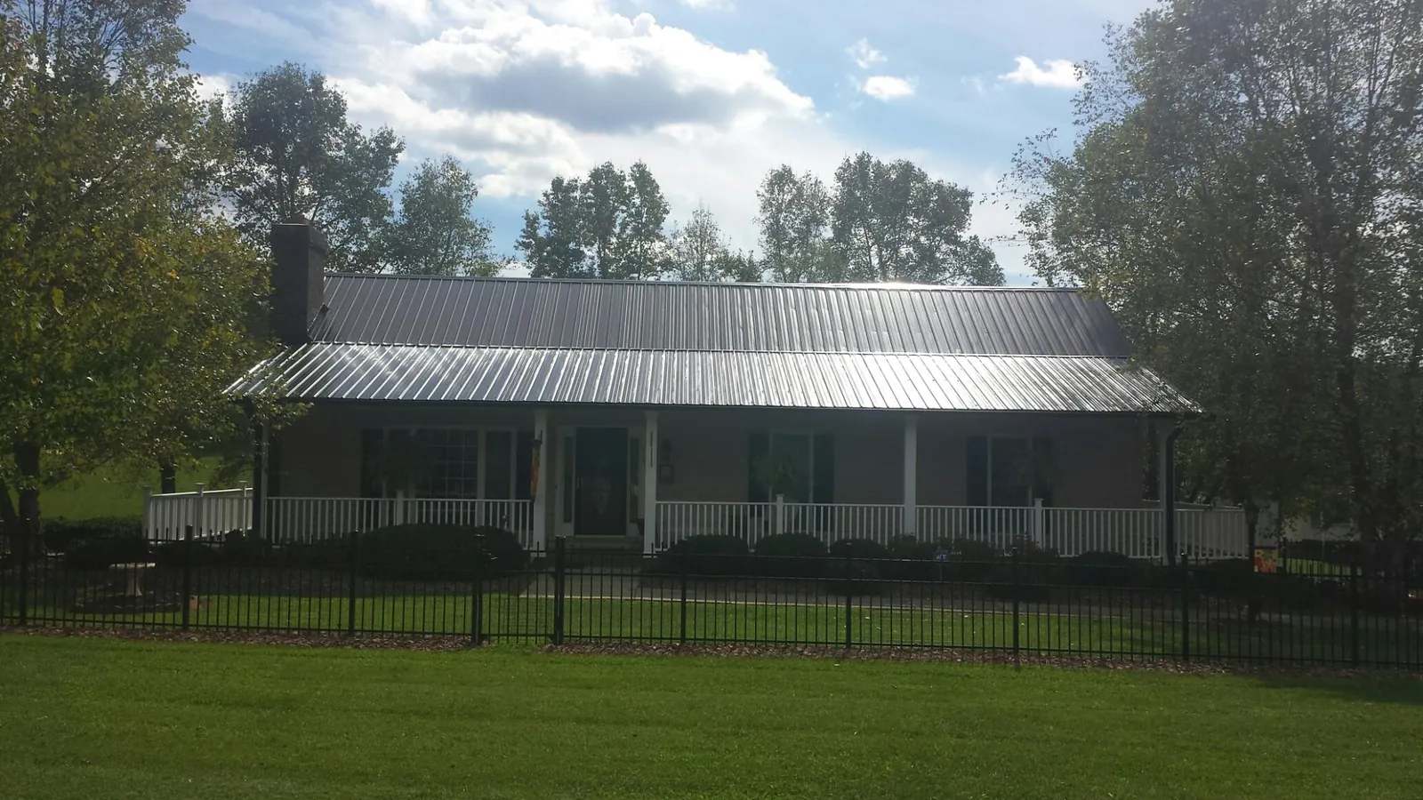 Gray metal roof on a brick ranch with a full width front porch — Gutter Guard Installation work by our crew in Shamokin