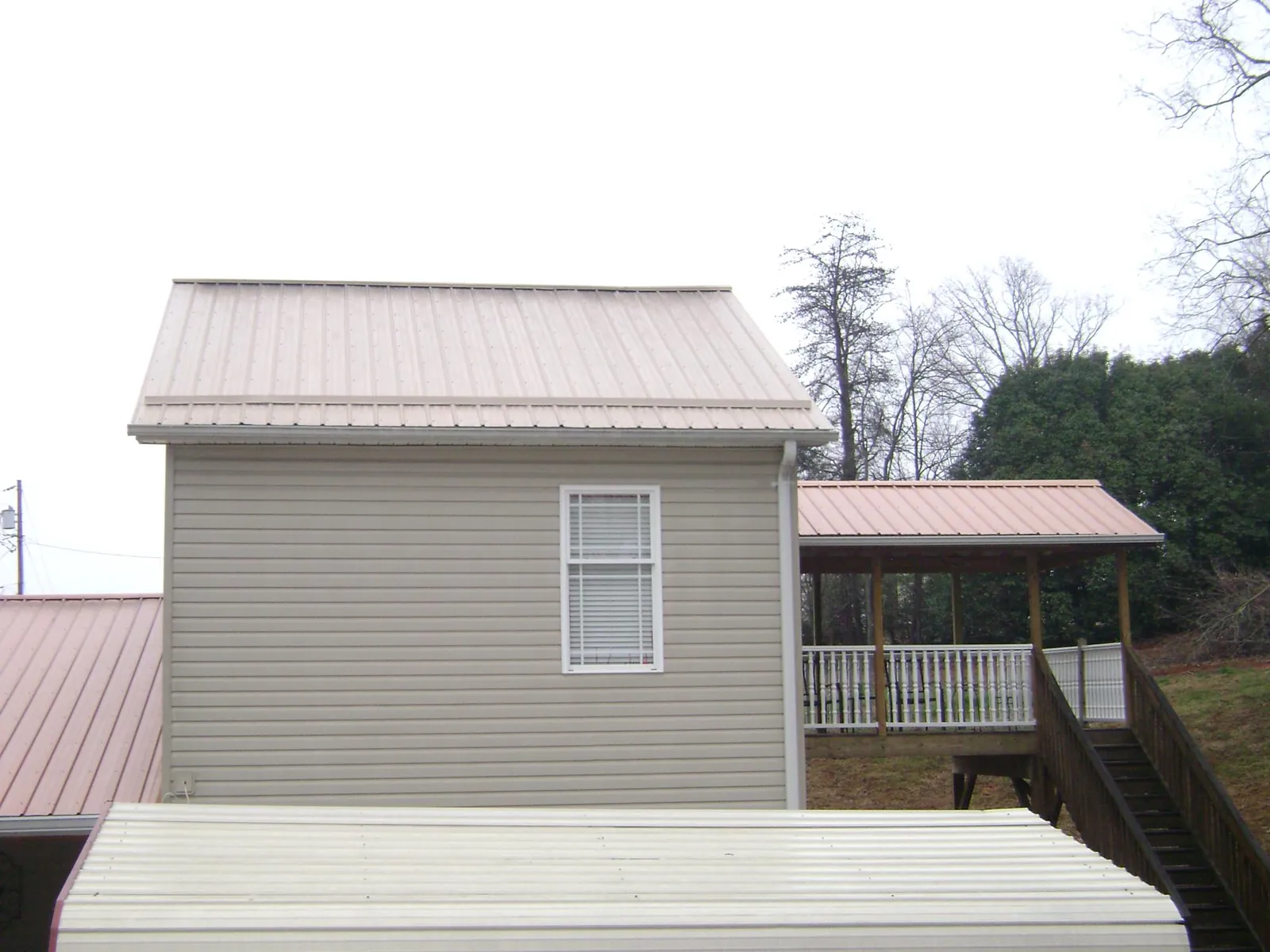 Tan metal roofs on a two story addition and attached porch, from a Roof Replacement job in Shamokin