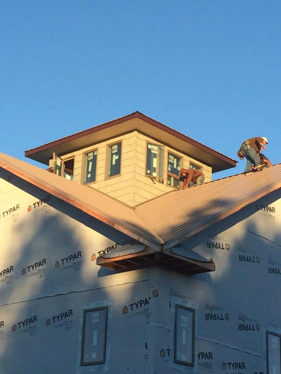 Roofers working around a rooftop cupola on a new metal roof at sunset — Roof Waterproofing in Shamokin by Roofing Brothers